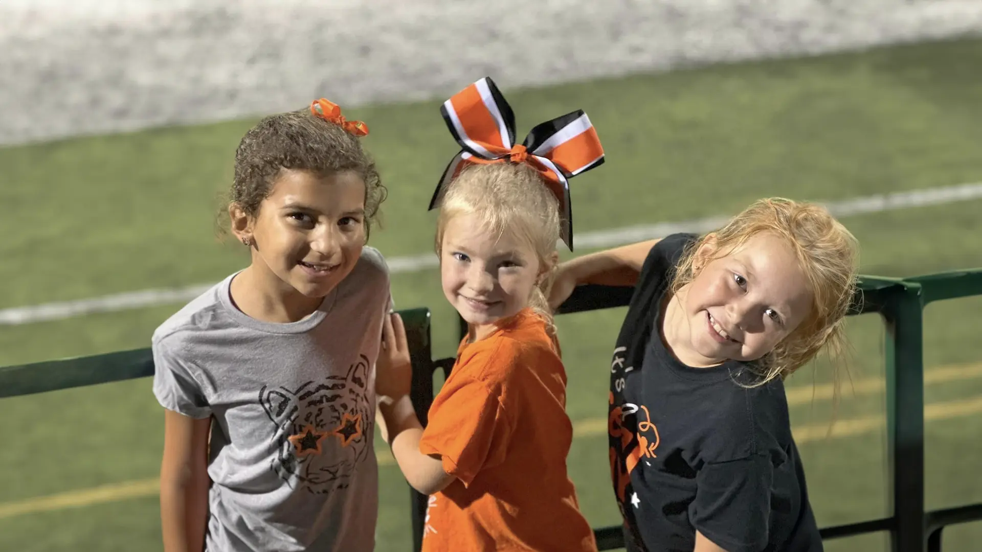 three young girls smiling at Tahlequah football stadium