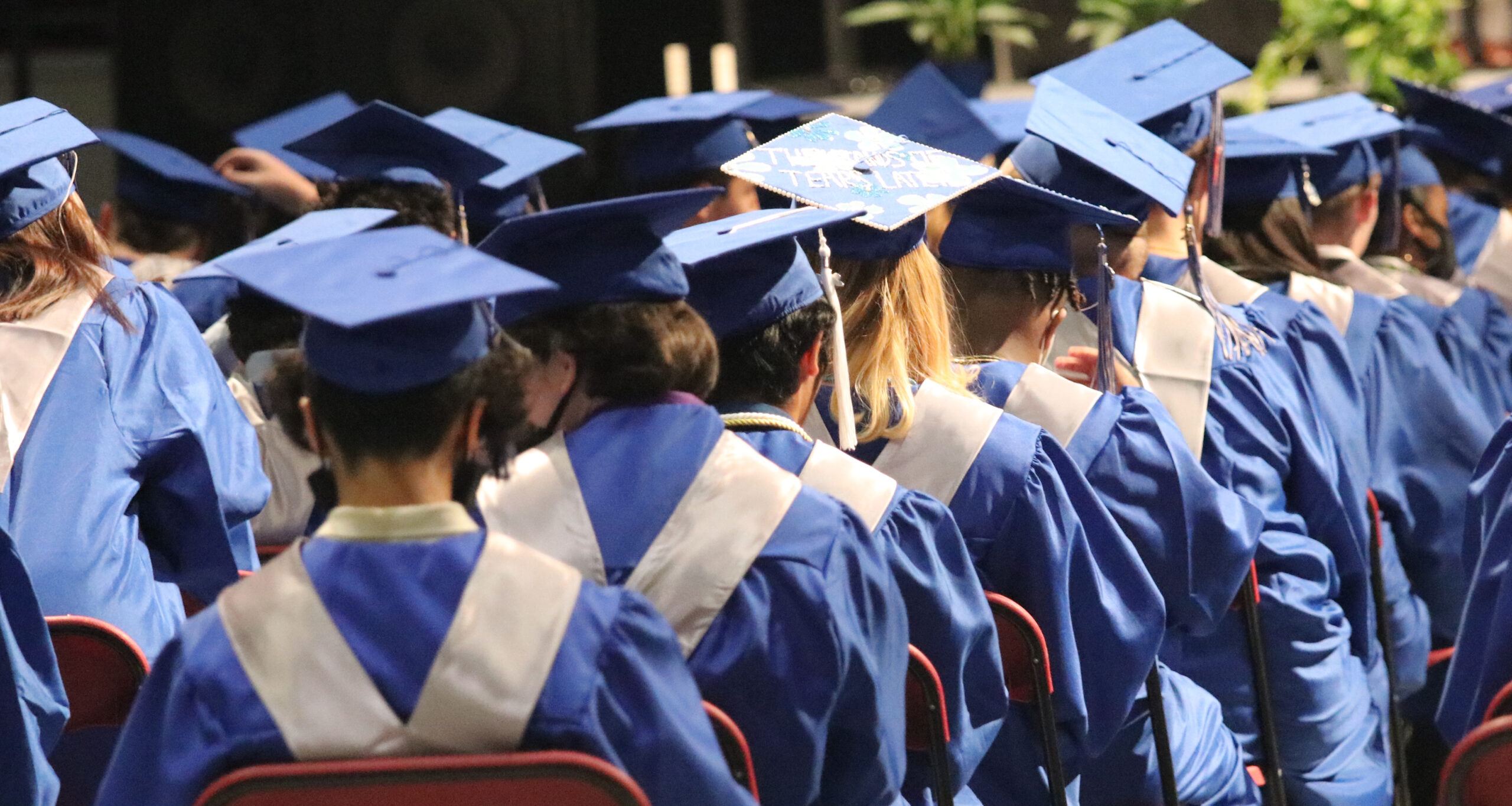 row of glenpool students wear blue graduation cap and gown.